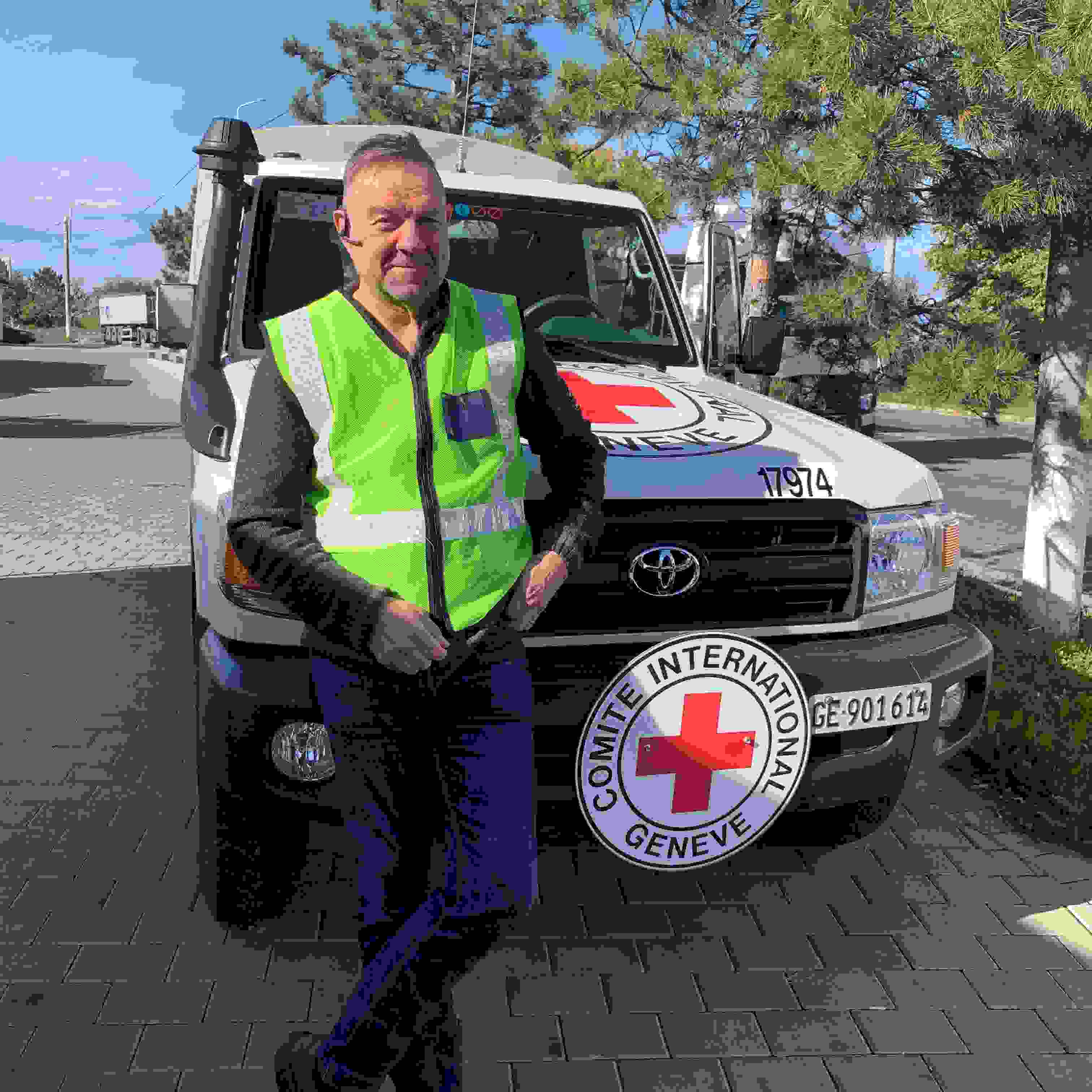 Aid worker Keijo Eklöf is smiling and standing in front of the International Committee of the Red Cross car.