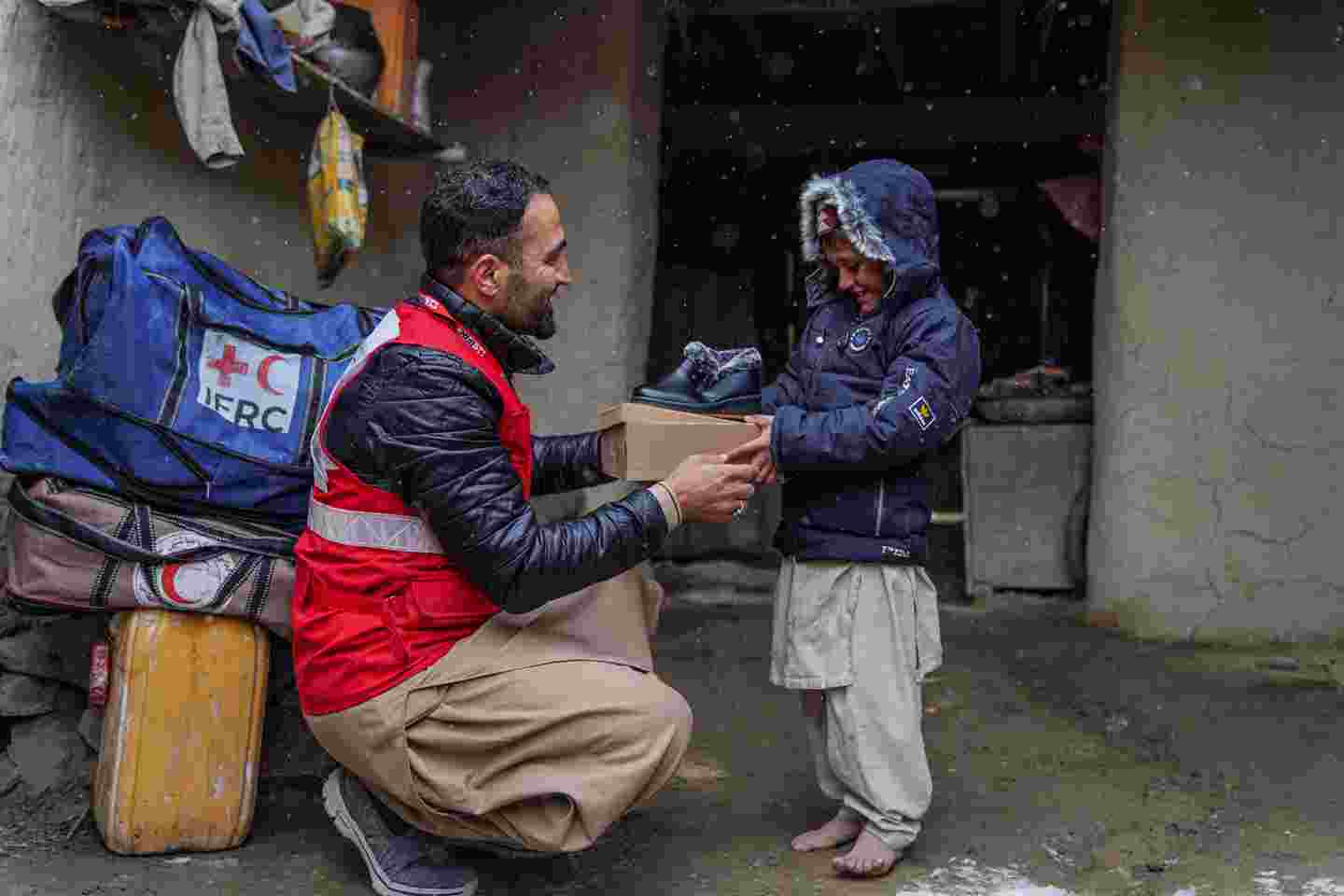 A Red Cross employee handing an aid package to a child.
