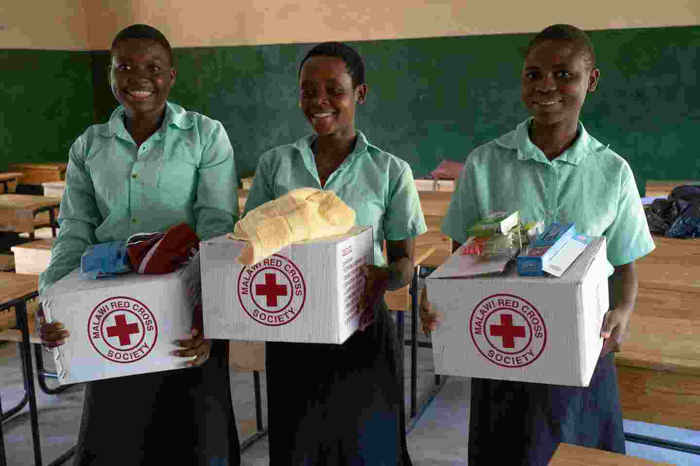 Smiling schoolgirls with hygiene packs.