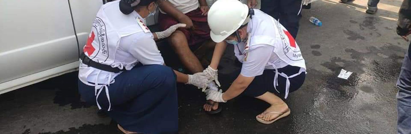 Red Cross aid worker feeding nutrient solution to a newborn baby.