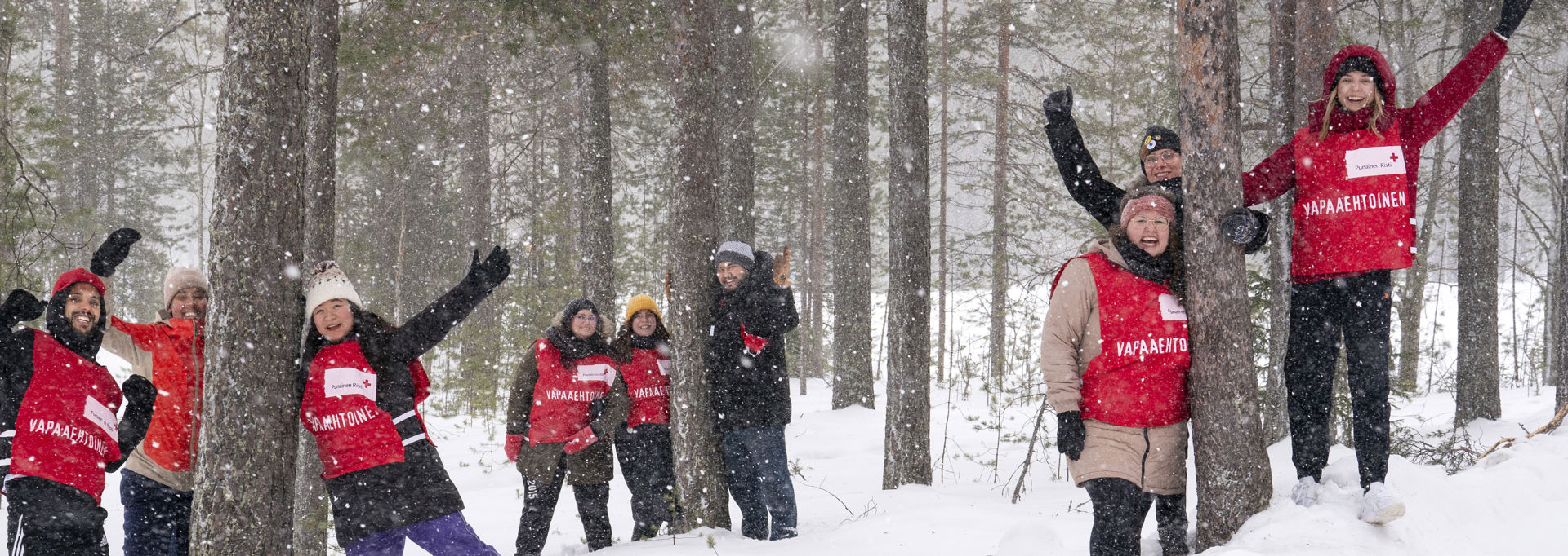 Red Cross volunteers at an outdoor event; one person in a red vest in the foreground with others visible behind.