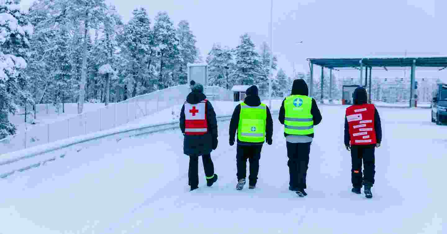 Two Red Cross volunteers and two Voluntary Rescue Service volunteers walking near the border area in winter conditions.