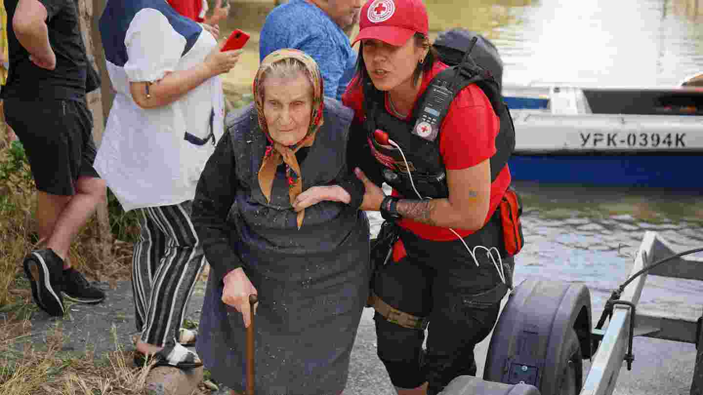 Red Cross volunteer helping an elderly person to walk.