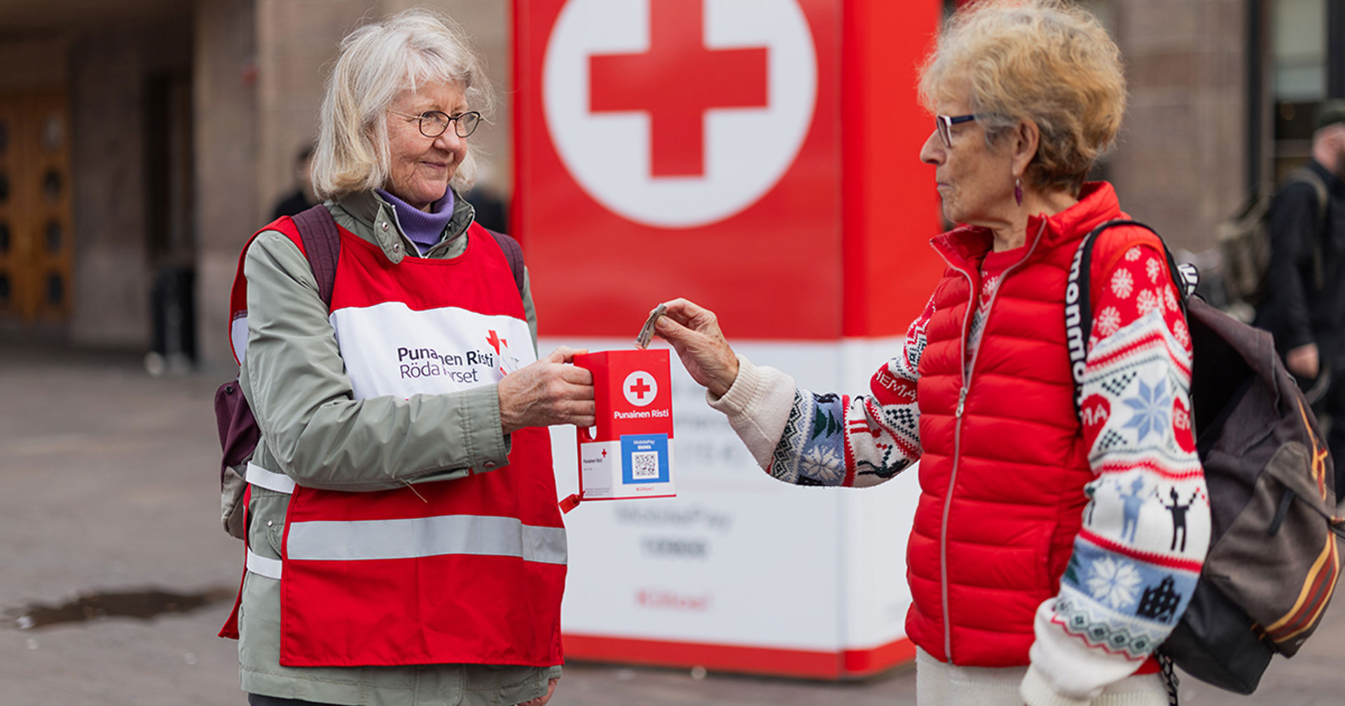 A person gives a donation to a volunteer collector's collection box.