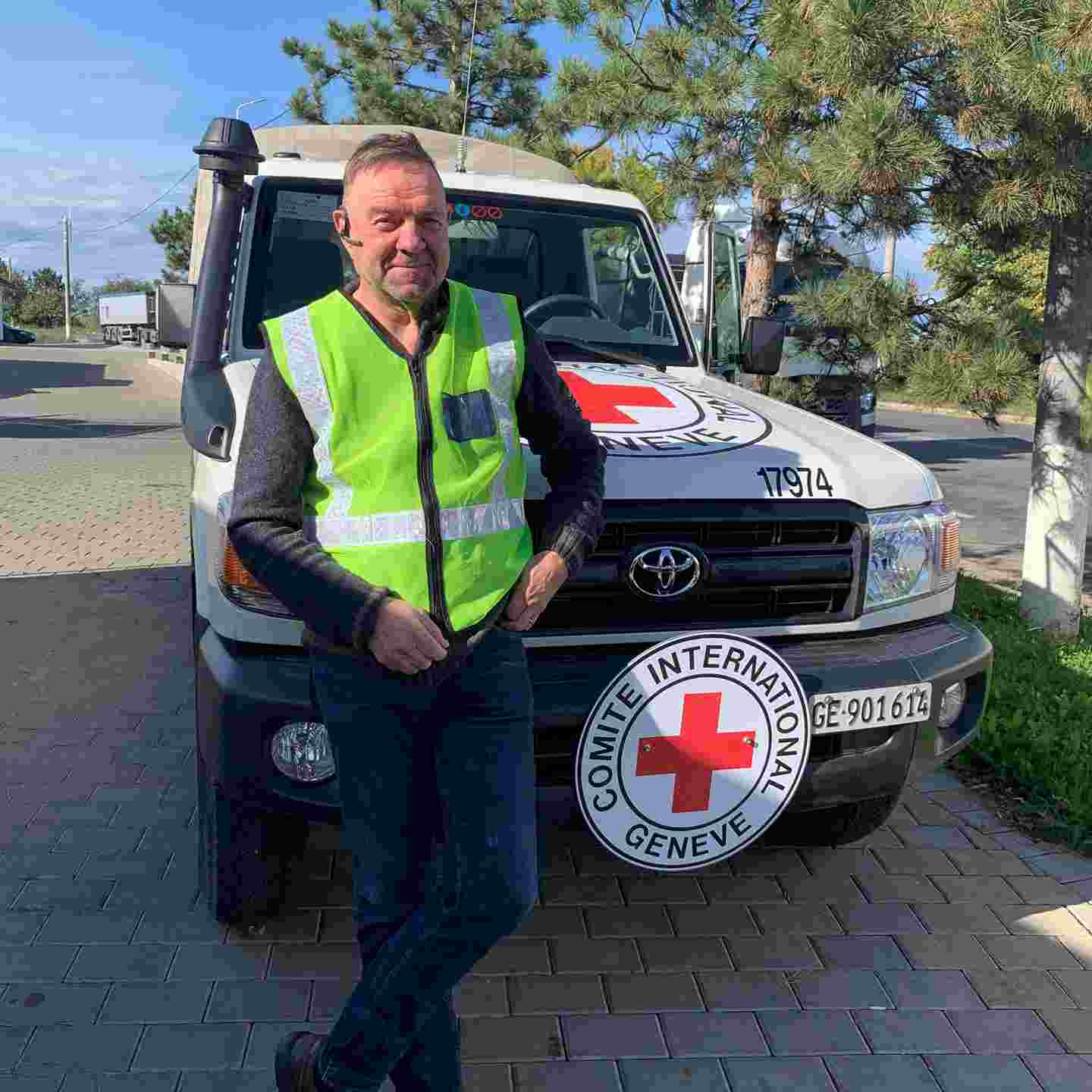 Aid worker Keijo Eklöf is smiling and standing in front of the International Committee of the Red Cross car.