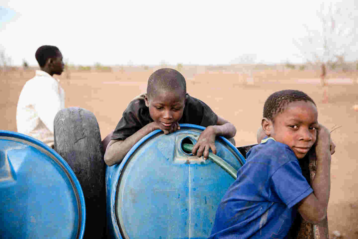 Zimbabwean boys by a water barrel.