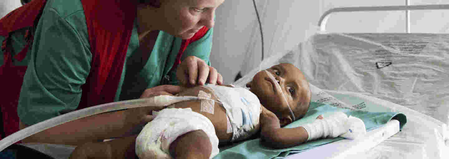 A Red Cross aid worker caring for a baby in a field hospital.