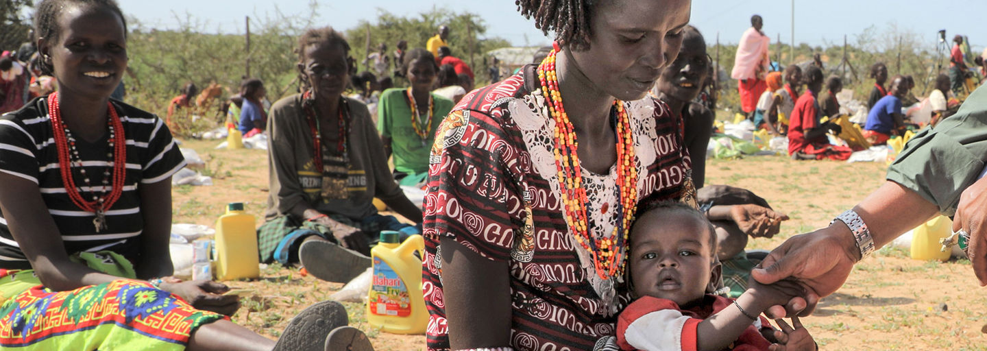 Aid worker feeding nutrient solution to a newborn baby.