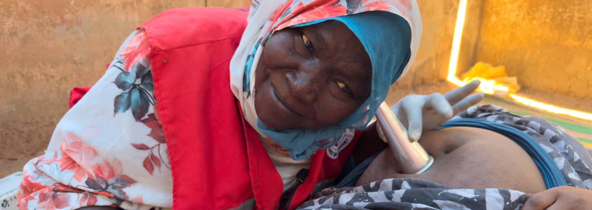 Two Red Cross volunteers in red vests, holding collection boxes. They are next to an about two-metre tall collection box.