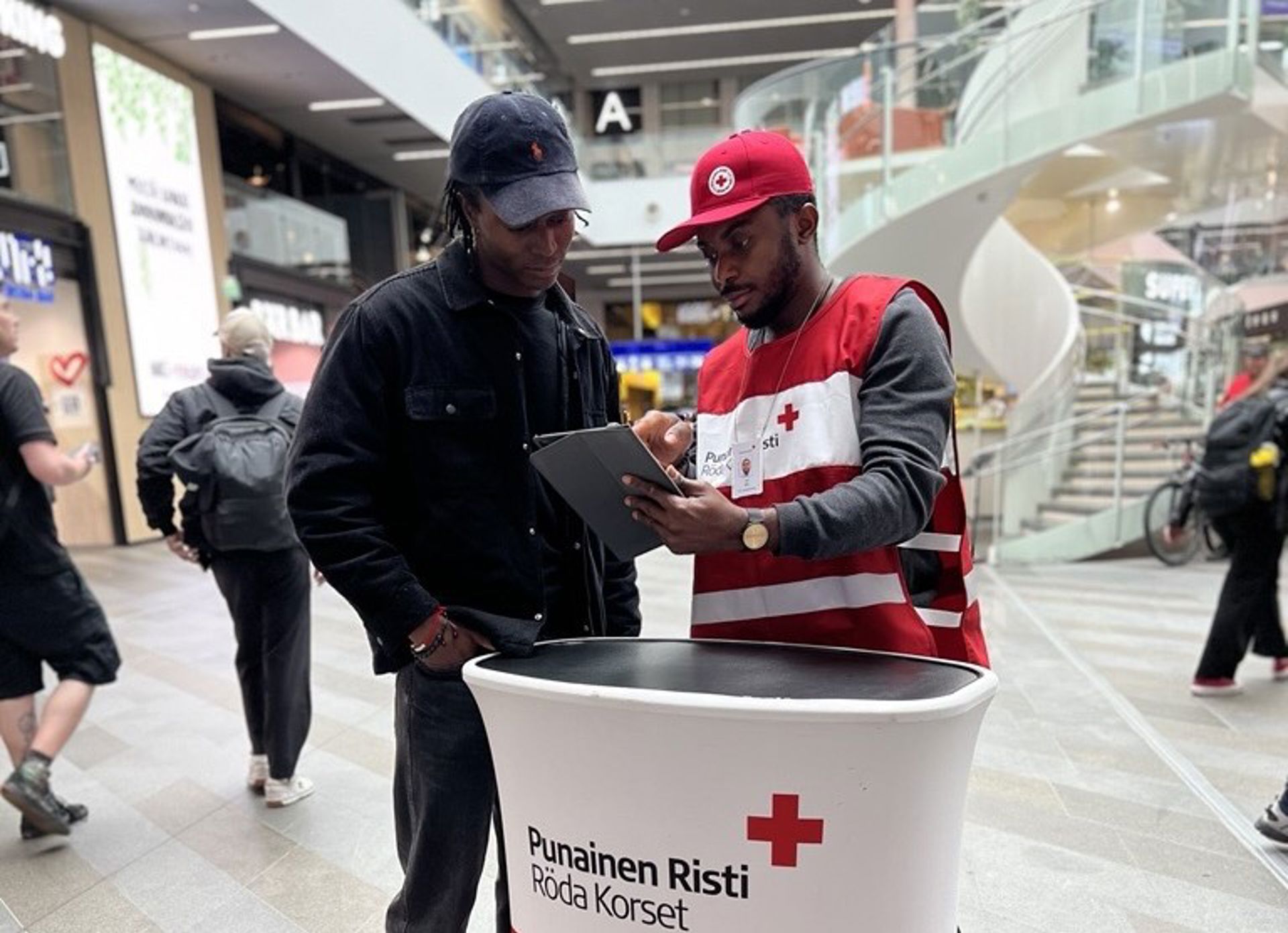 Three Red Cross face-to-face fundraisers standing on a street with red folders and wearing blue Red Cross face-to-face fundraiser vests.