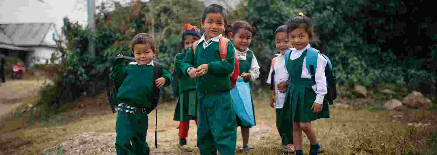 Smiling Nepalese children wearing school uniforms on their way to school.