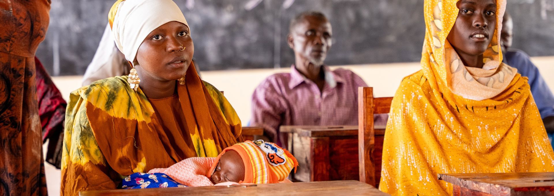 Two Red Cross volunteers in red vests, holding collection boxes. They are next to an about two-metre tall collection box.