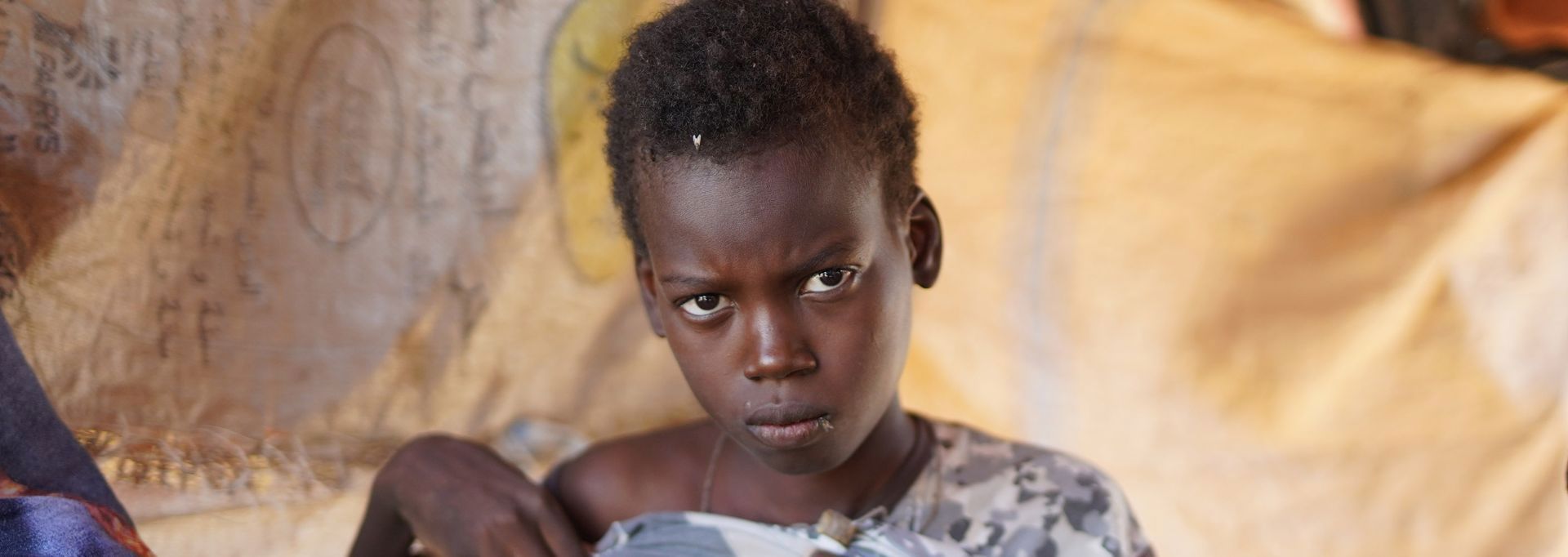 Two Red Cross volunteers in red vests, holding collection boxes. They are next to an about two-metre tall collection box.