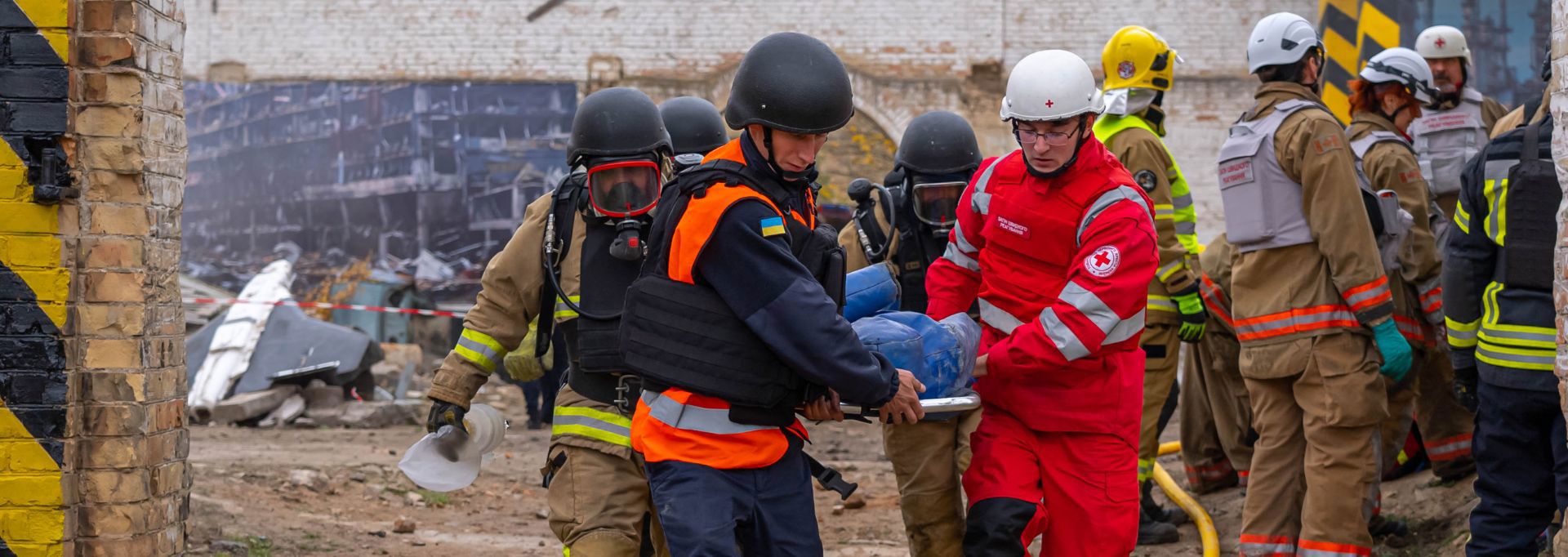 Two Red Cross volunteers in red vests, holding collection boxes. They are next to an about two-metre tall collection box.