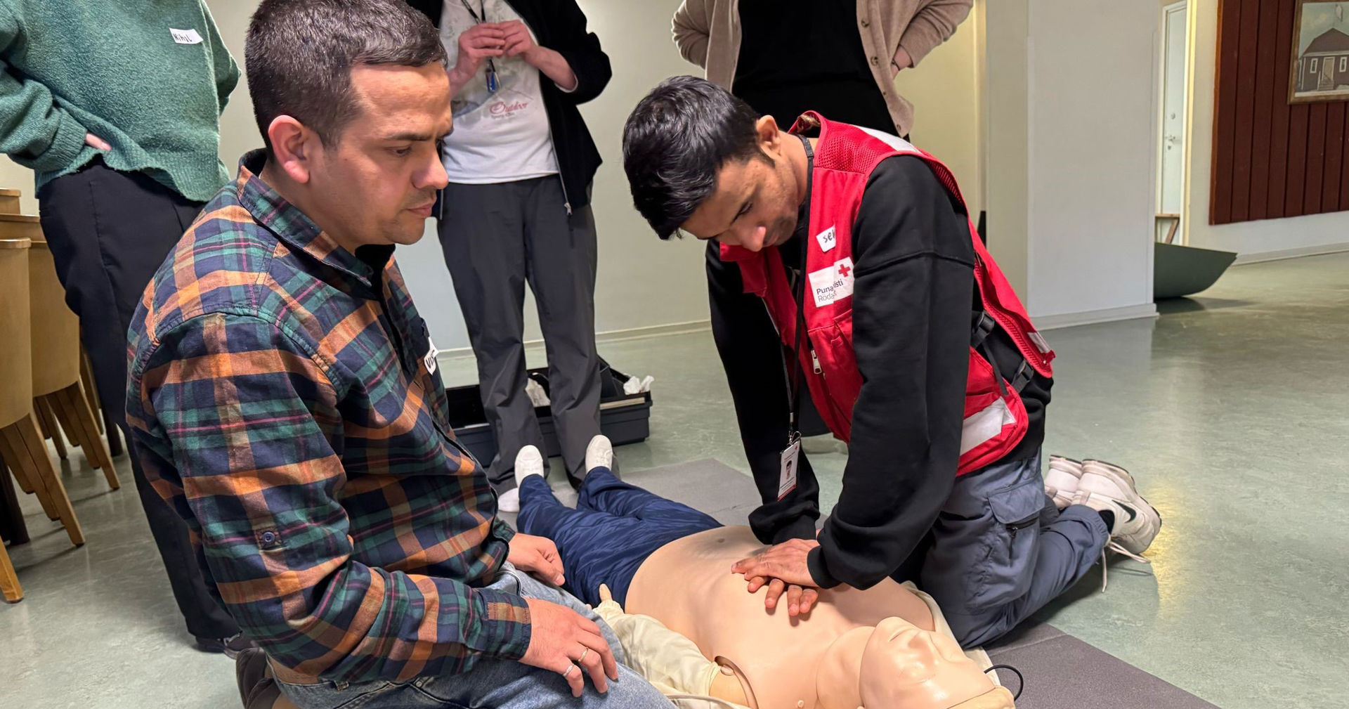 Sebastian Rosanthan demonstrates CPR on a training mannequin during a first aid session, while others observe closely.