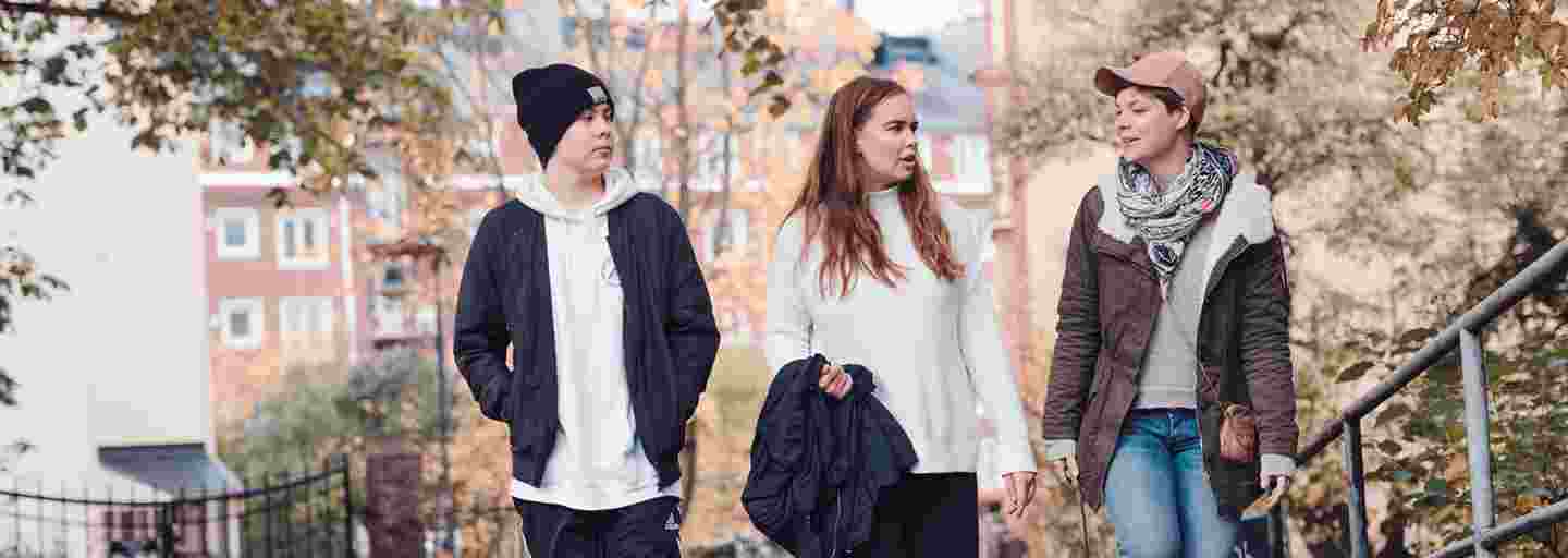 Three young people walking outside in a sunny autumn weather.