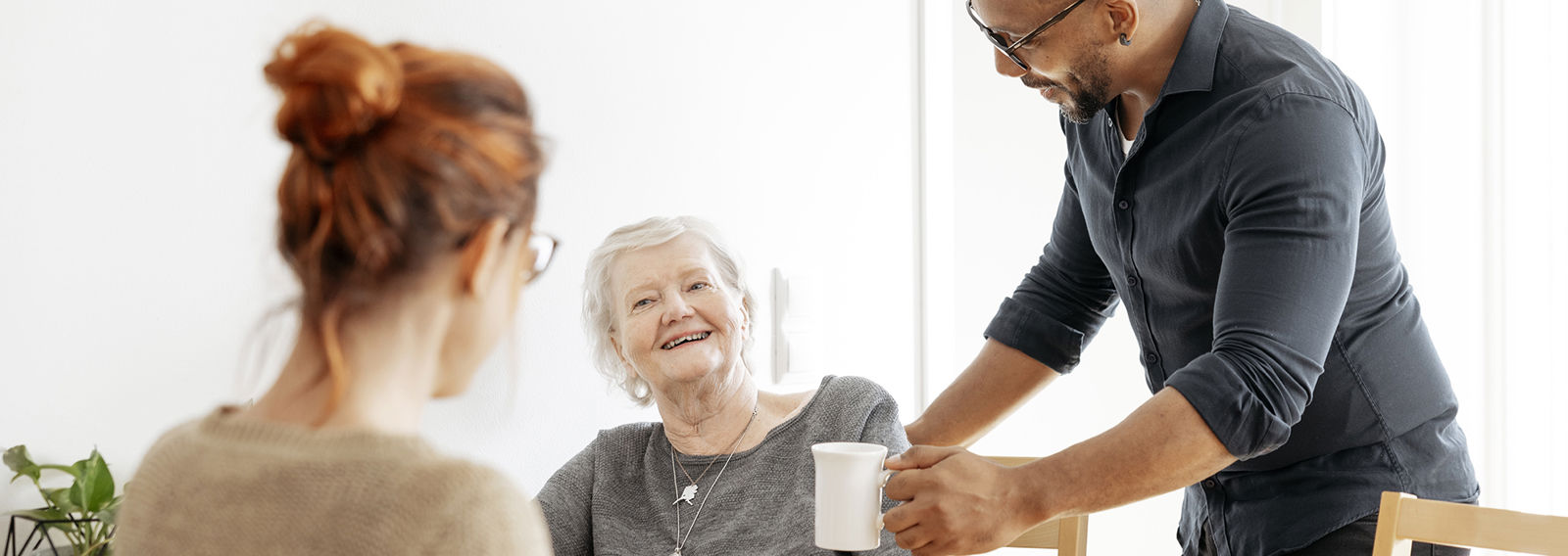 Two women standing side by side in a wintry landscape. The younger woman, wearing a Red Cross volunteer vest, is looking gently at the older woman.