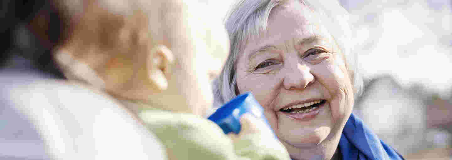 A smiling elderly woman with a small child and its mother.