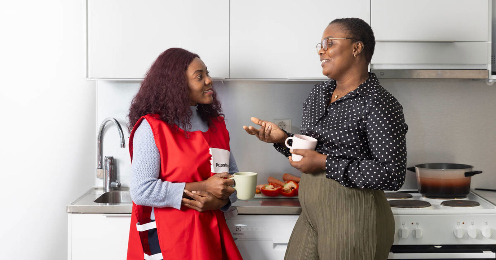 Three immigrant women cooking together with a Red Cross volunteer.