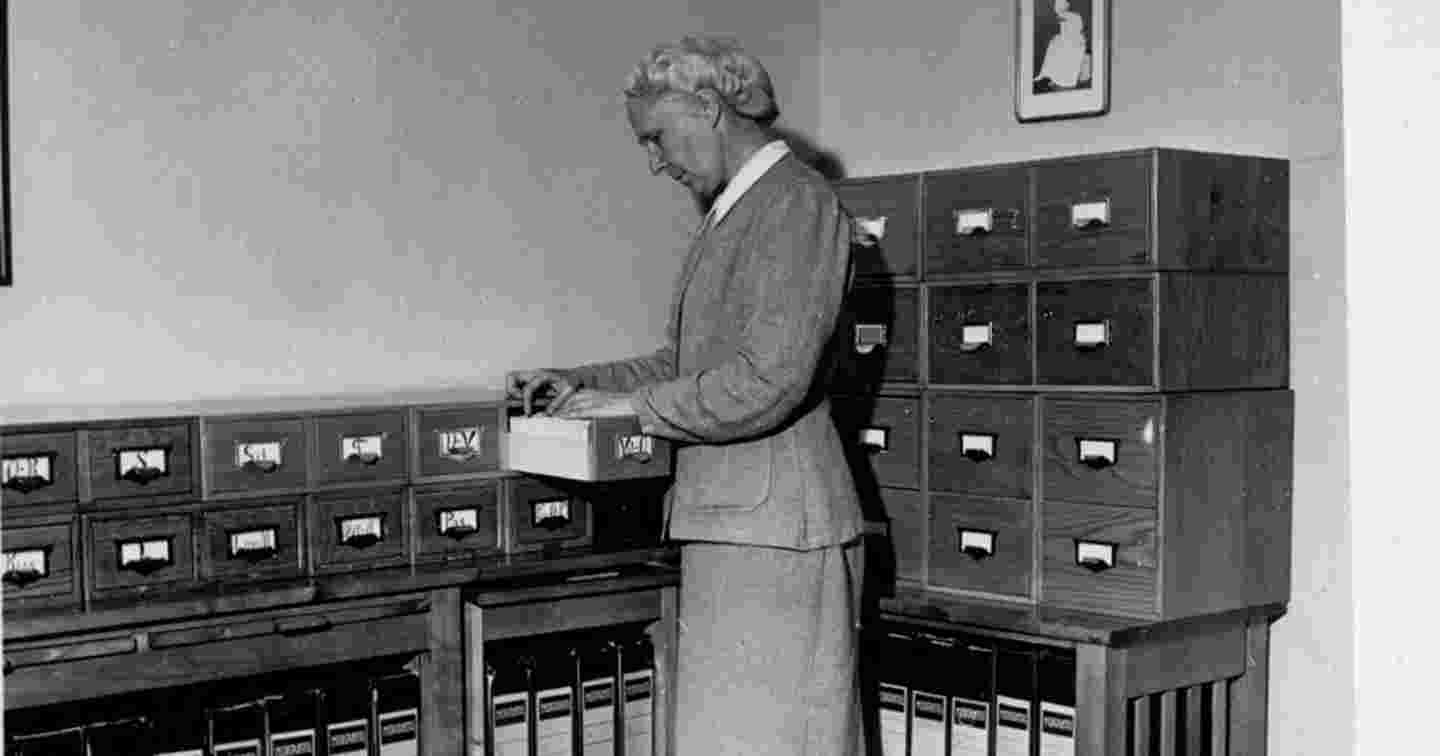 An old black-and-white photo of a person working on a nurse card file.
