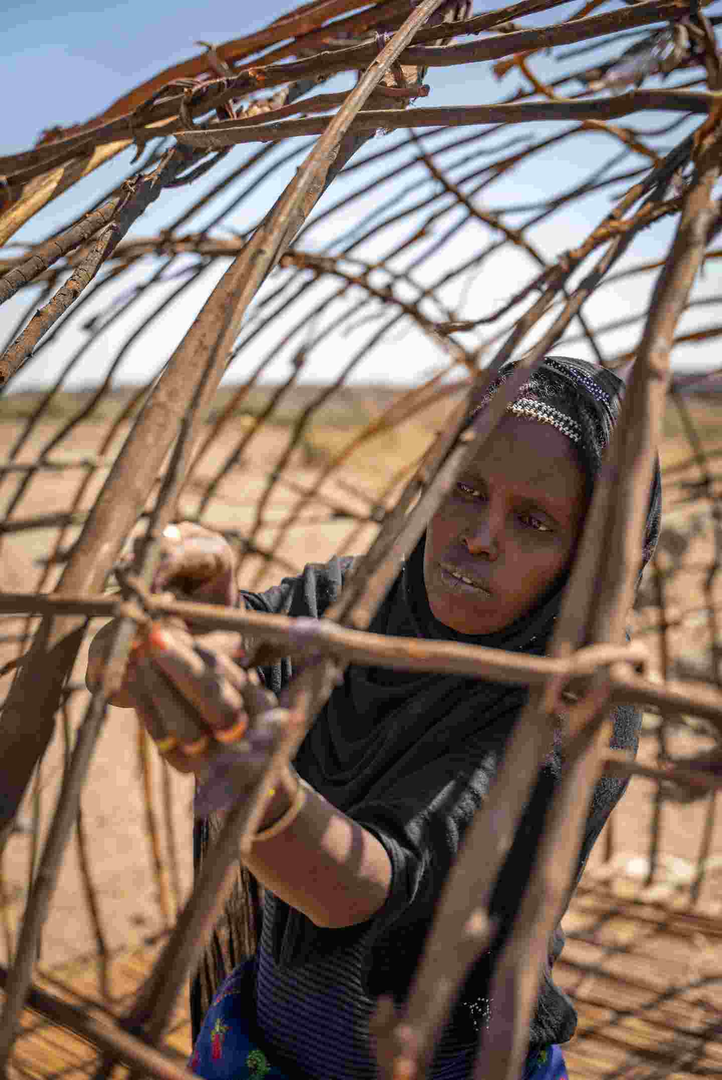 A woman fixing the wooden structure of her house.
