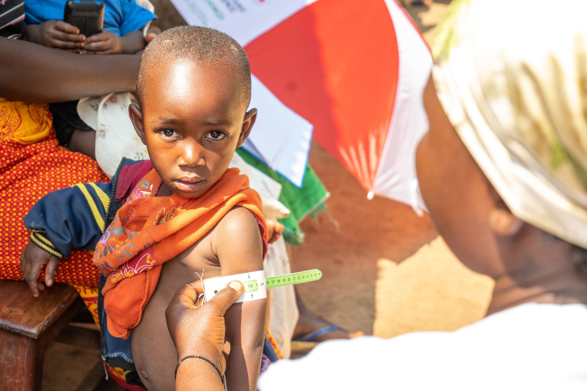 A woman measuring the arm circumference of a small child.