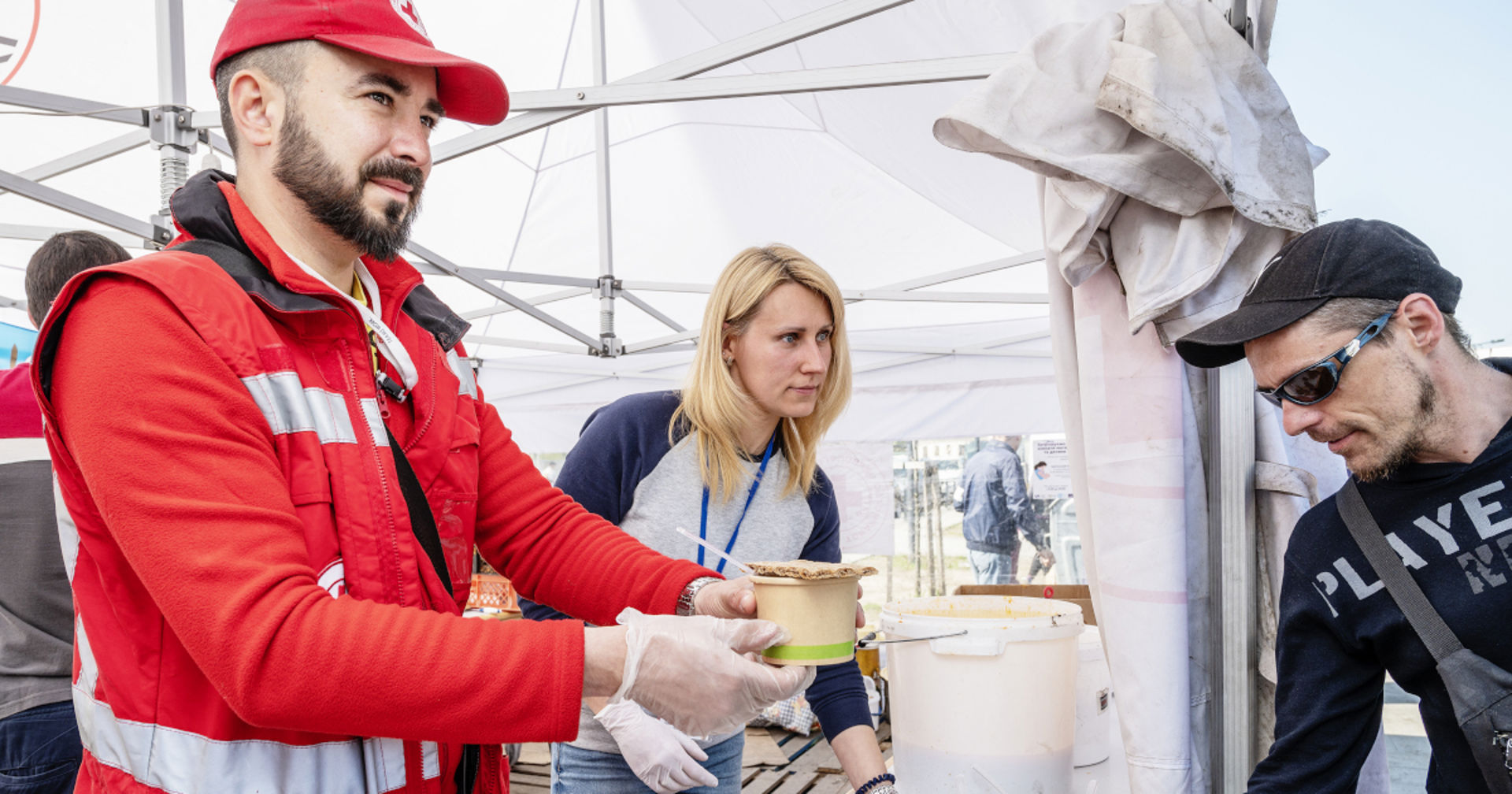 A man and a woman distributing food in a tent.