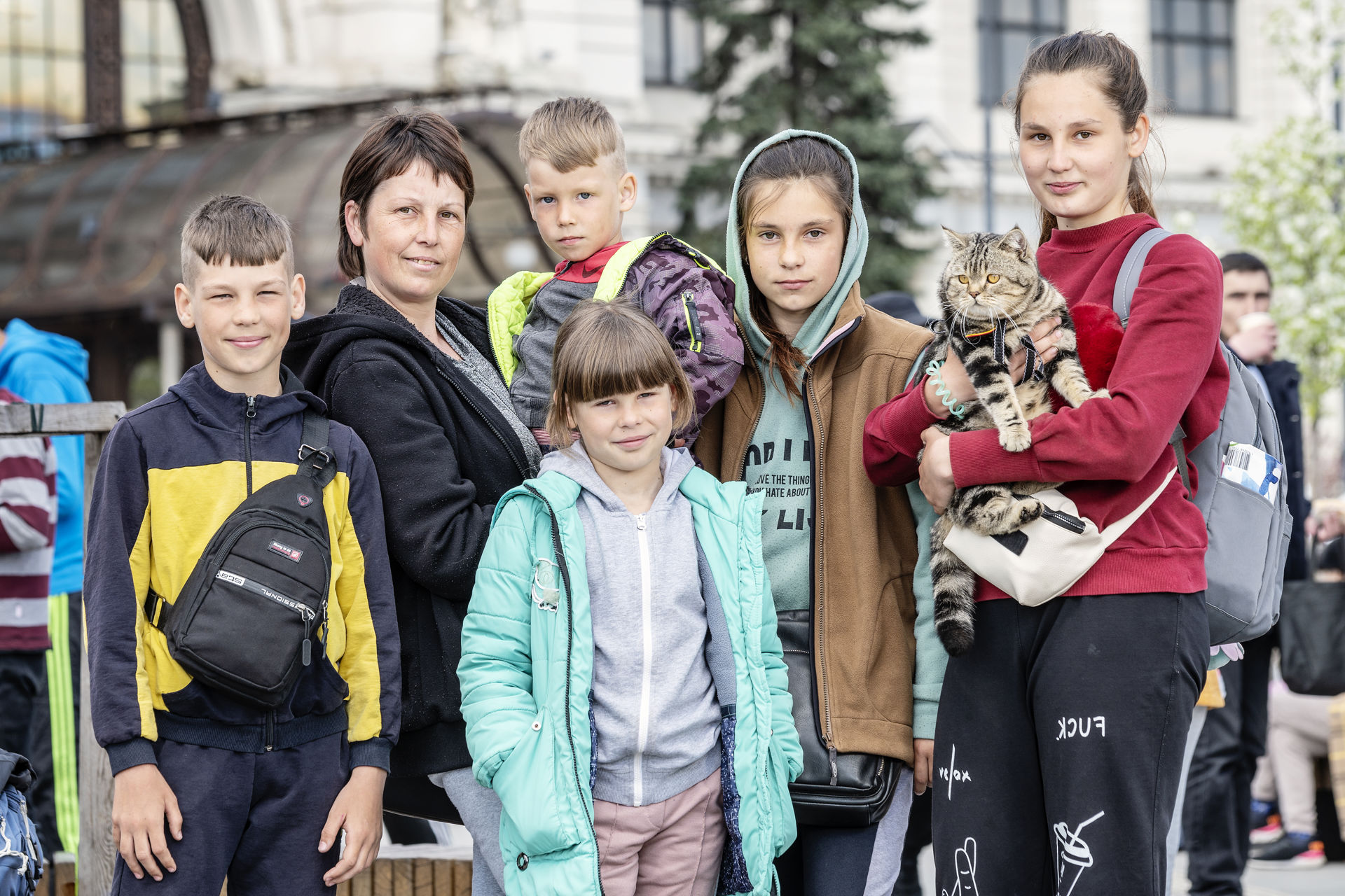 A mother, five children and a cat standing in a line.