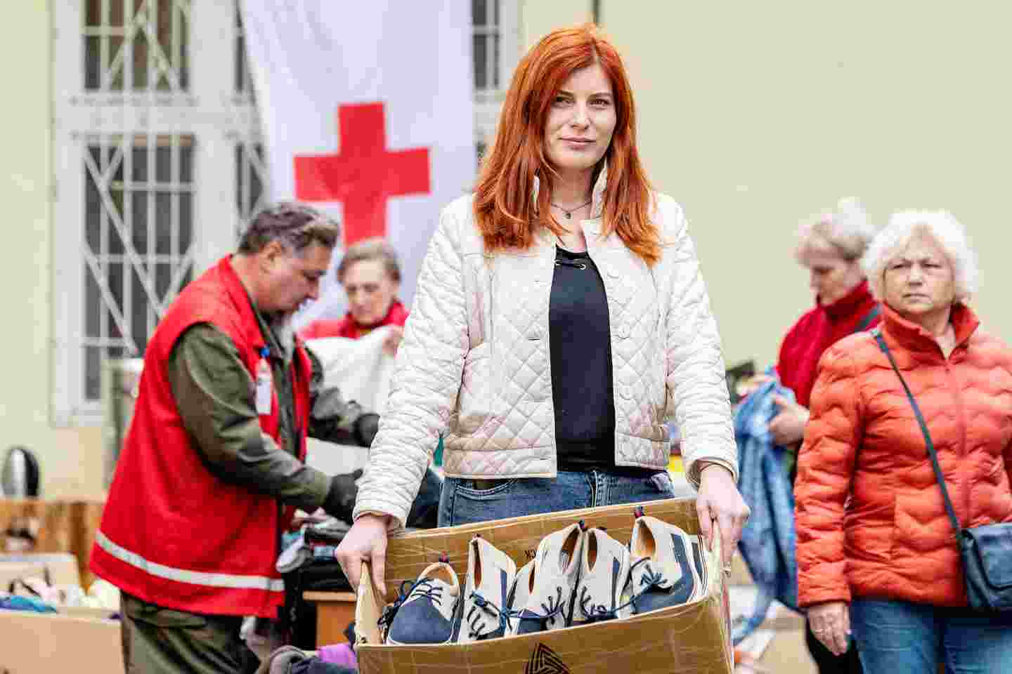 A woman holding a shoe box with people in the background.