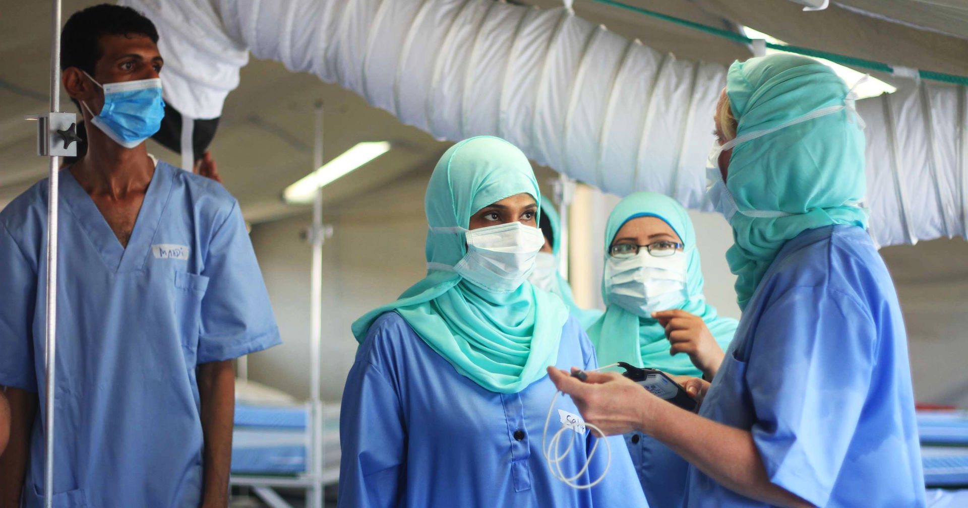 Four Red Cross workers in a hospital with protective gear.