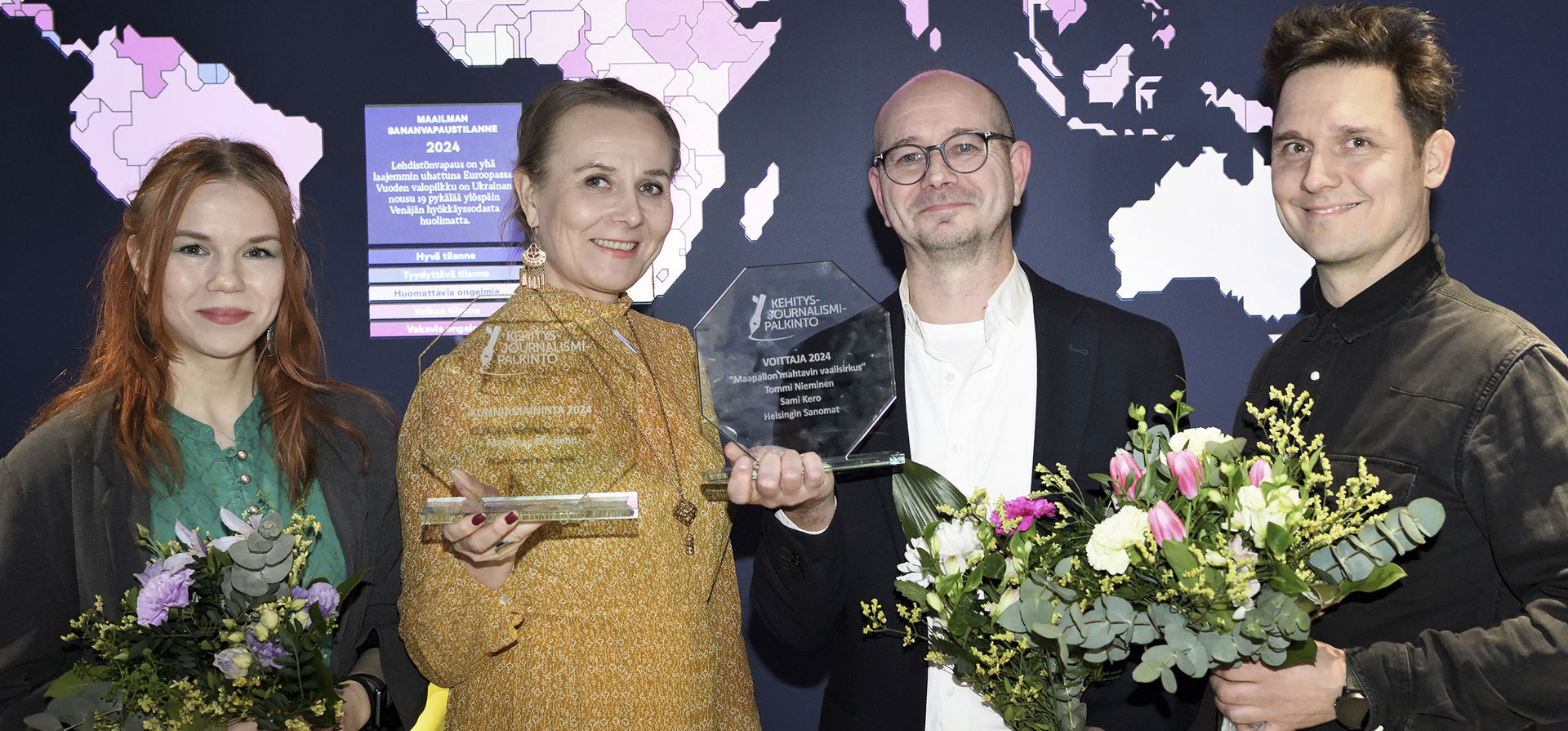 The 2024 awardees stand in line with their awards and bouquets of flowers.