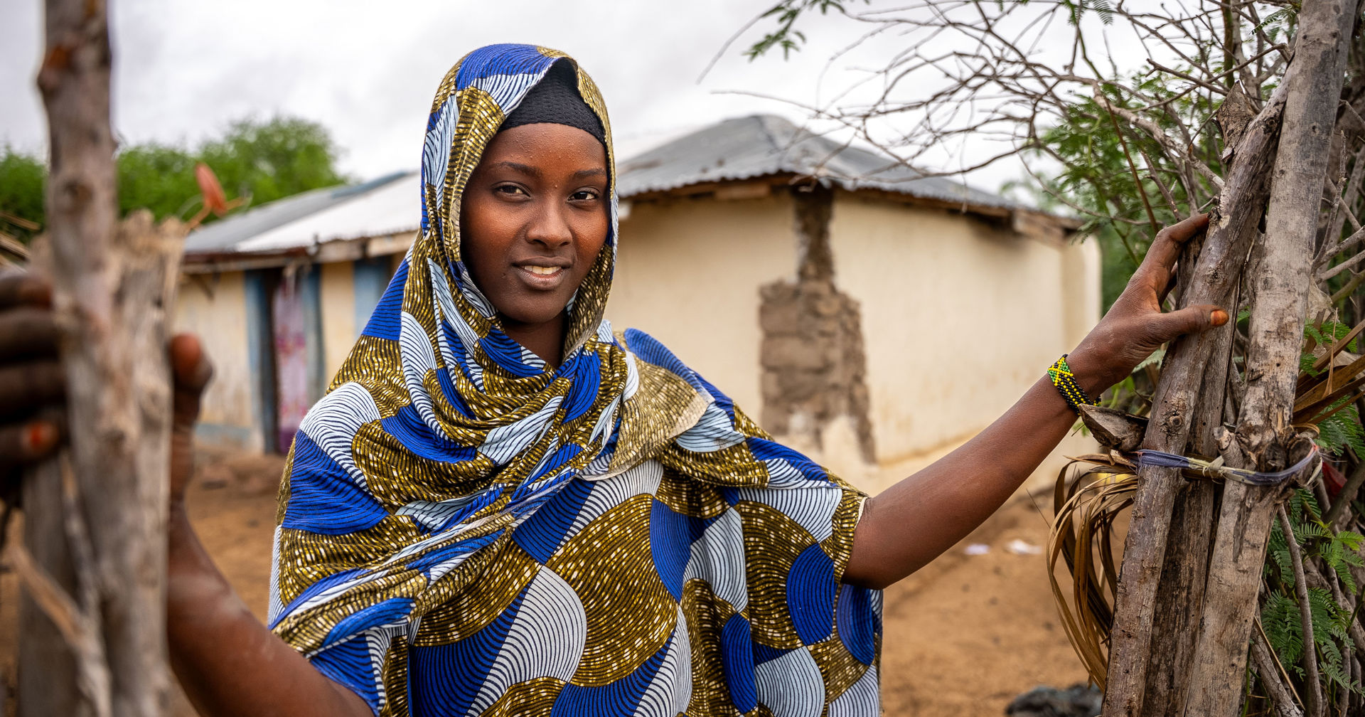 Hawo Yussuf stands in the yard of her renovated house and smiles.