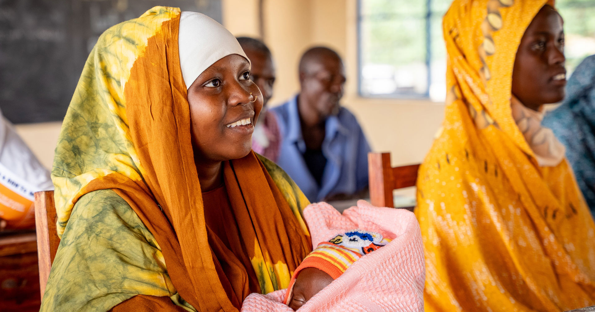 A smiling farmer, wearing overalls and holding a hoe.
