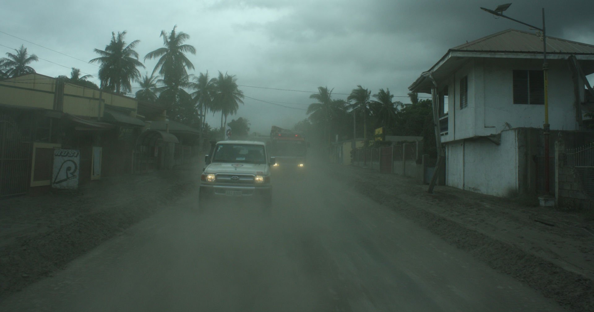 A Red Cross car is driving a road with smoke and darkness around.