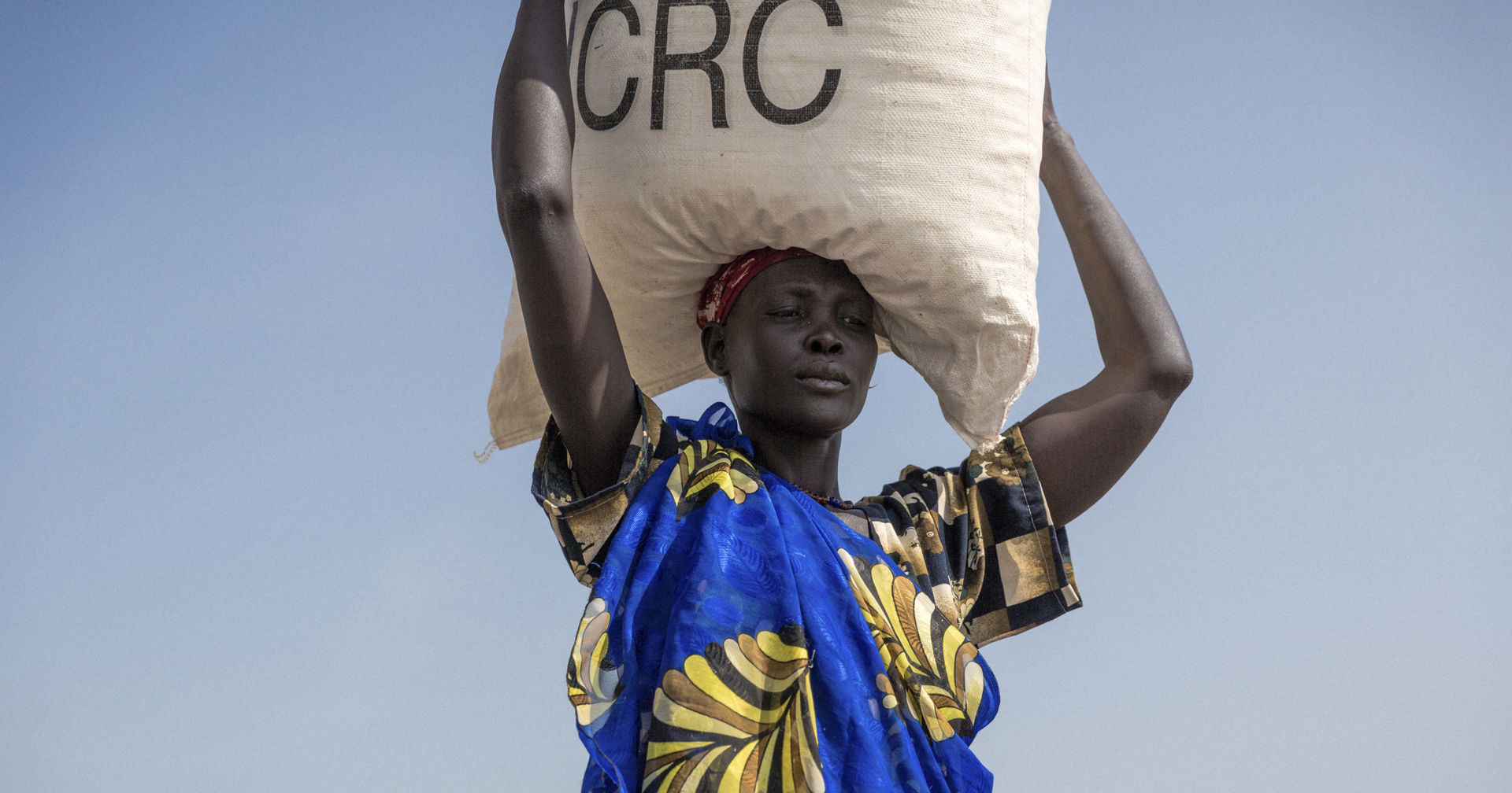 A person carrying a Red Cross food aid bag on their head.