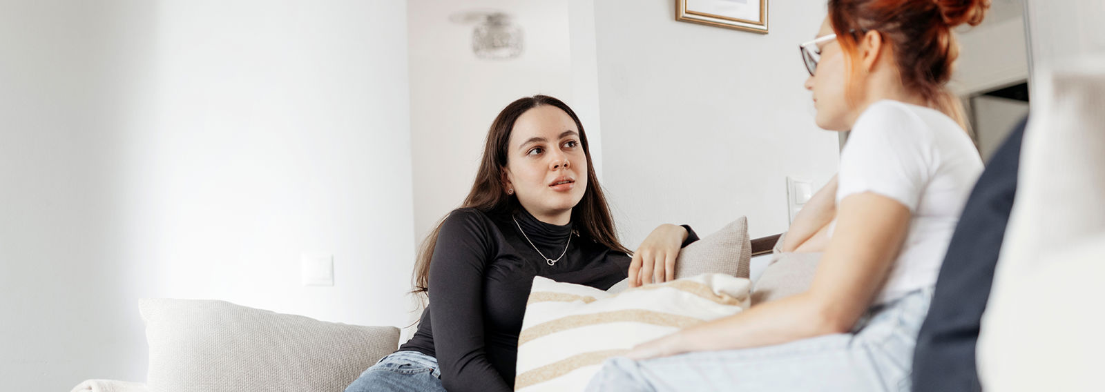 A young person talking to an adult and both are sitting on a couch